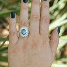 An 18k white gold blue zircon ring with double diamond halo.