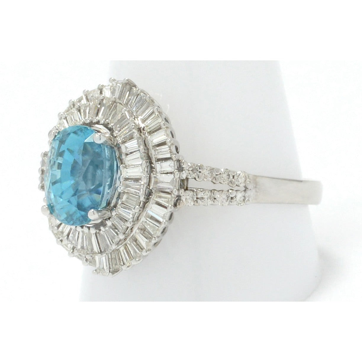 This statement ring has 2 halos of diamonds surround this large oval blue zircon.