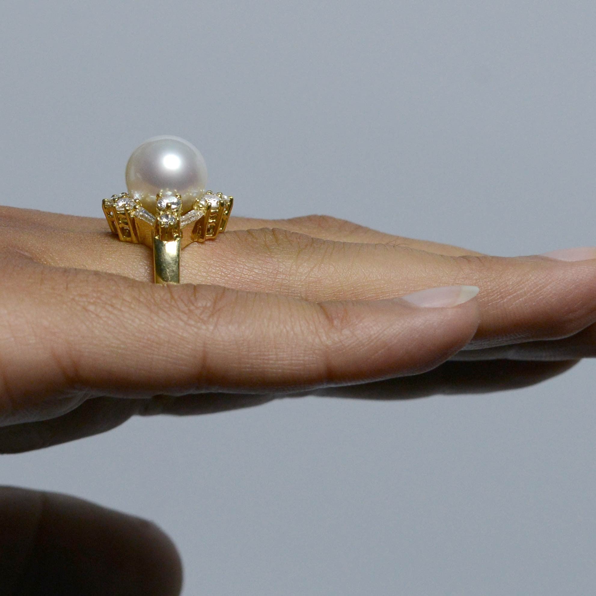 A white, natural south sea pearl in a diamonds & 18k yellow gold ring setting.