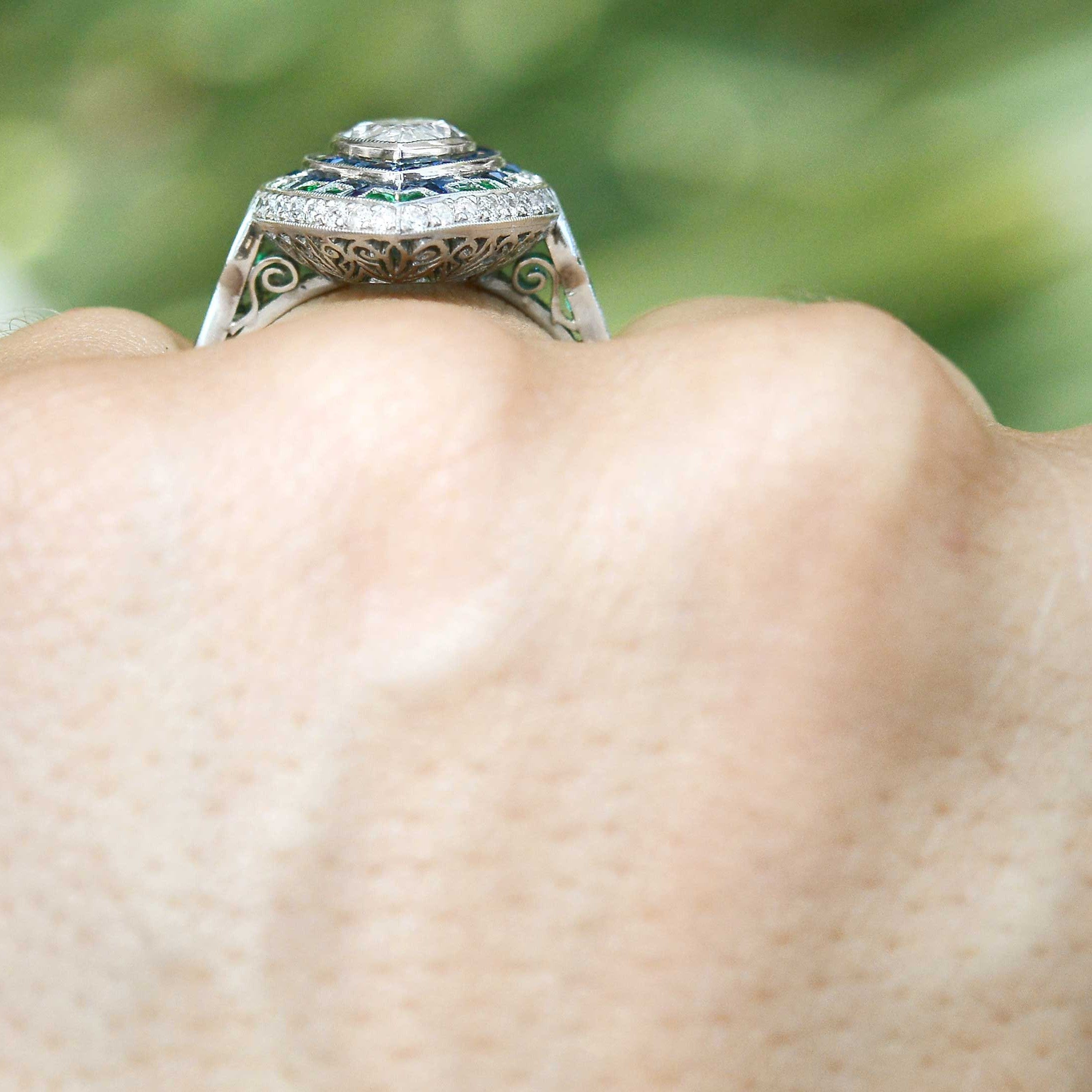 A navette shaped diamond and platinum wedding ring with blue sapphire and emerald accent gems.