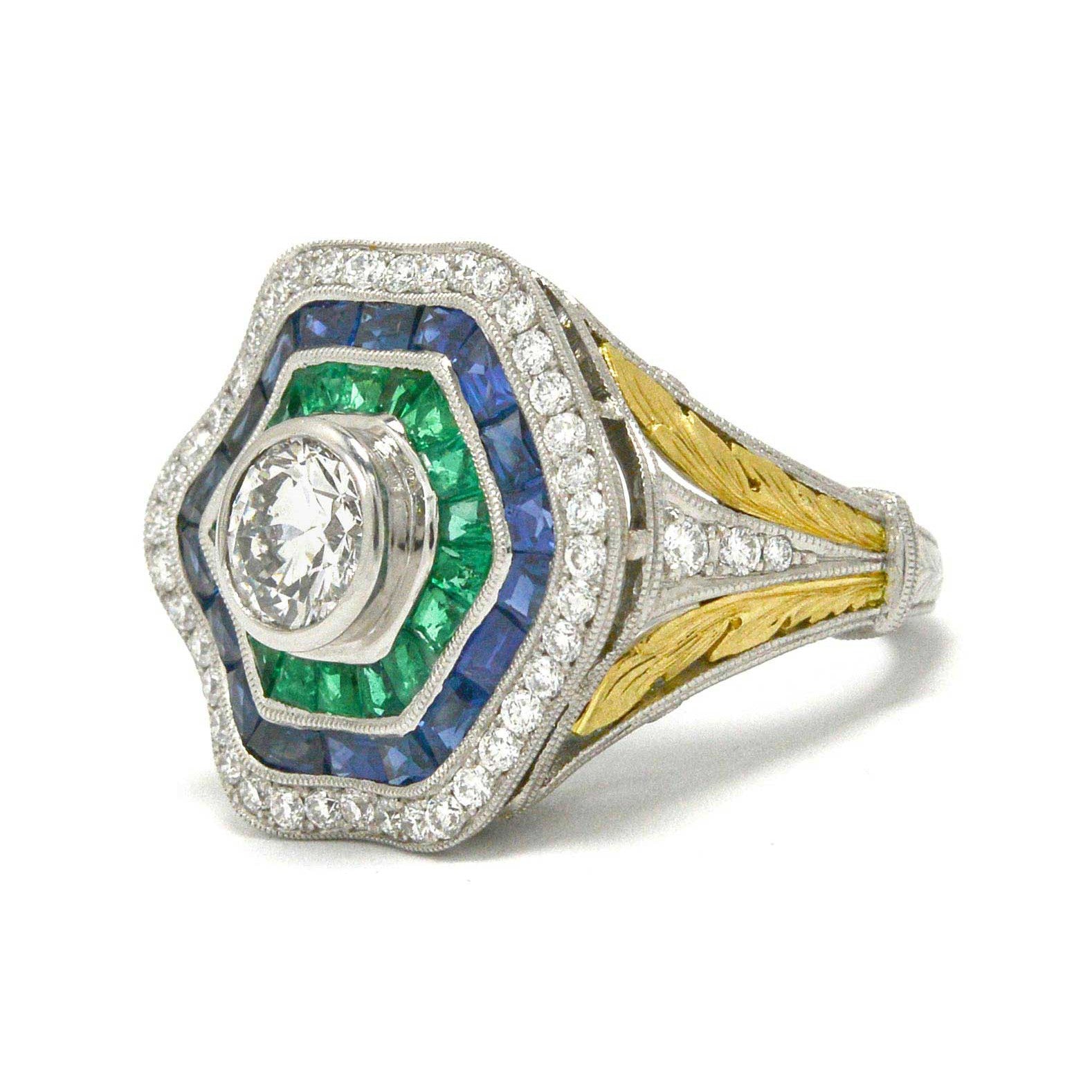 A 1 carat round brilliant diamond hexagon ballerina ring with emeralds and sapphires.