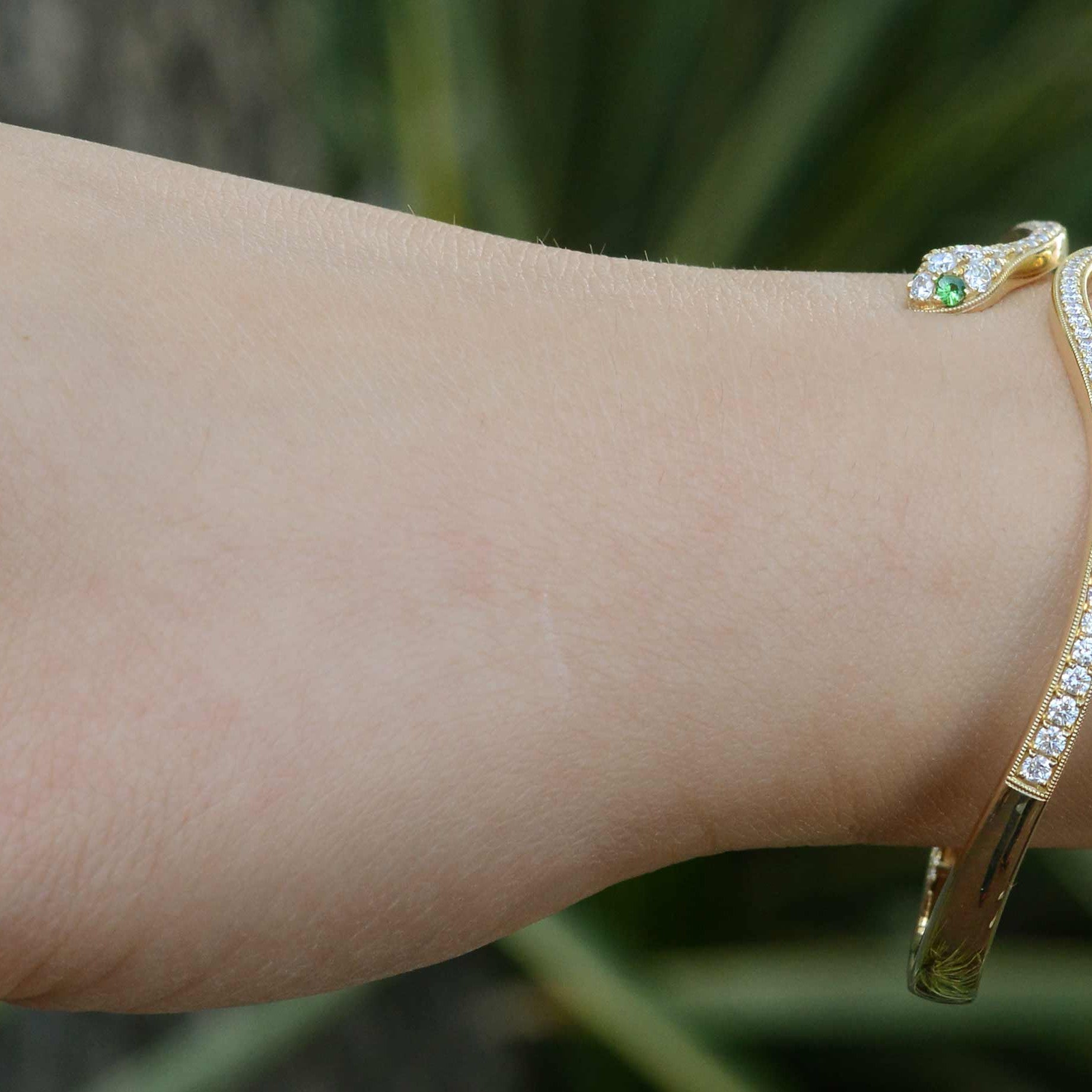 A modern snake bracelet with green tsavorite gemstone eyes.